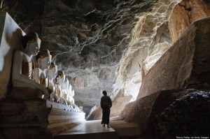 A man walks past Buddha images inside Ya The Byan cave